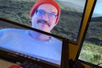 A man in an orange hat on a computer monitor.